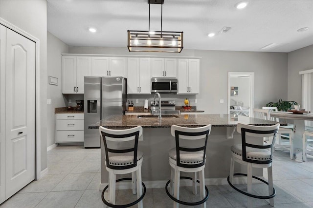 626 Ocean Jasper Dr, Saint Augustine, FL 32086 - kitchen featuring stainless steel appliances, an island with sink, white cabinetry, dark stone counters, and recessed lighting