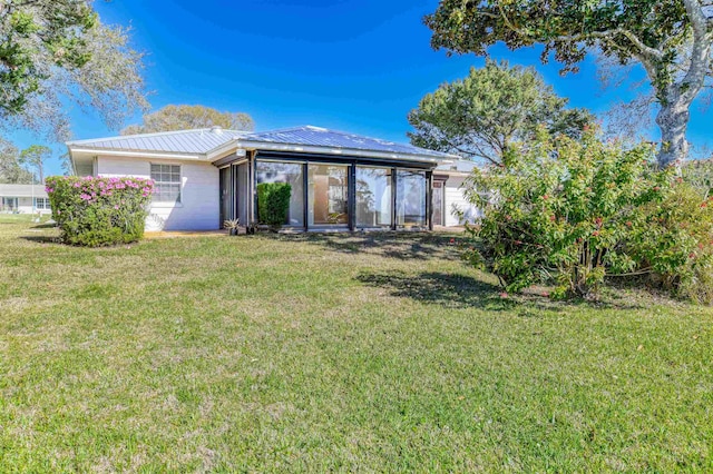 rear view of house featuring metal roof, a yard, and a sunroom