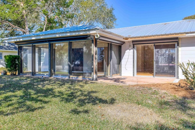 back of house with a lawn and metal roof