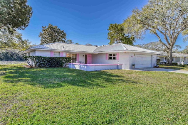 single story home with a front yard, metal roof, driveway, concrete block siding, and an attached garage