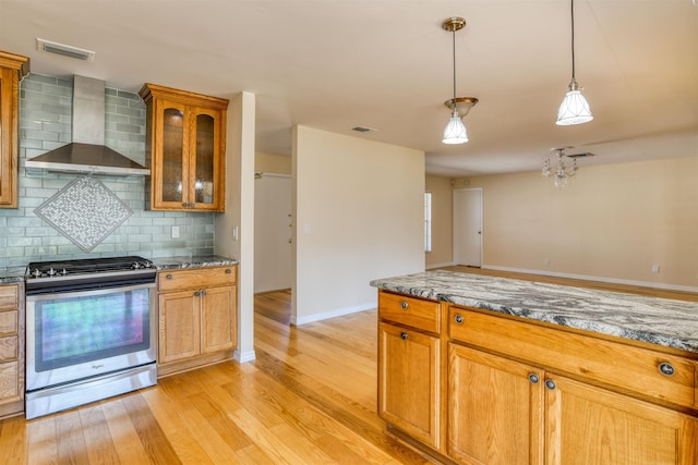 kitchen with light wood finished floors, visible vents, gas stove, and wall chimney exhaust hood