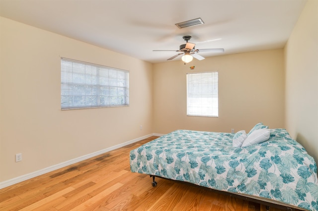 bedroom with ceiling fan, visible vents, baseboards, and light wood-style flooring