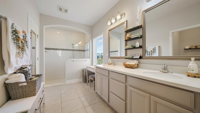 bathroom with tile patterned floors, a walk in shower, double vanity, and a sink