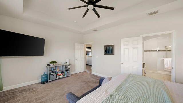 carpeted bedroom with a tray ceiling, baseboards, visible vents, and connected bathroom