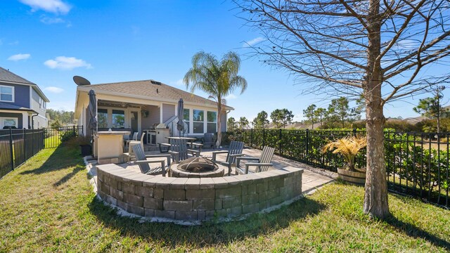 back of property featuring a yard, a patio area, a fenced backyard, and an outdoor fire pit