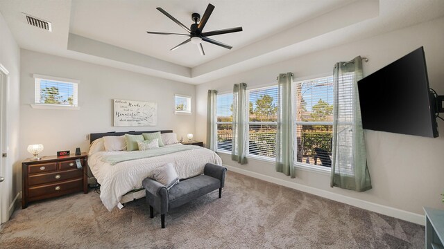 carpeted bedroom featuring visible vents, a raised ceiling, multiple windows, and baseboards