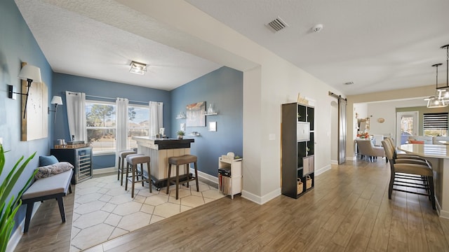 dining space with a barn door, baseboards, visible vents, and light wood-type flooring