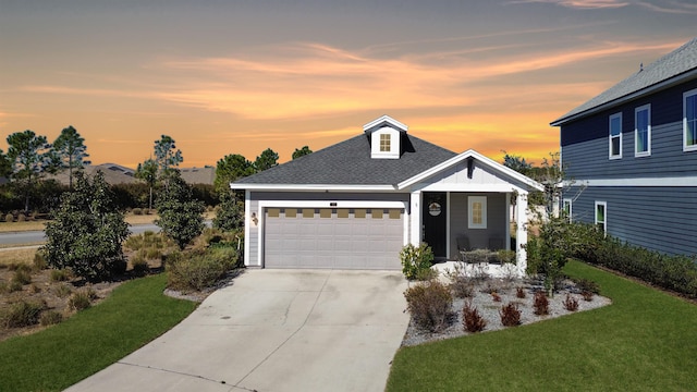 view of front facade with a yard, a garage, driveway, and a shingled roof