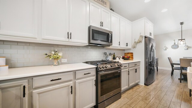 kitchen with decorative backsplash, light countertops, white cabinets, appliances with stainless steel finishes, and light wood-type flooring