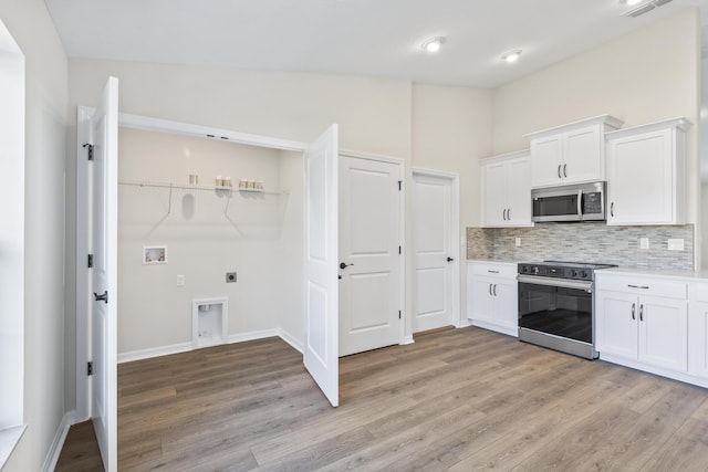 kitchen with tasteful backsplash, stainless steel appliances, light wood-style floors, white cabinets, and light countertops