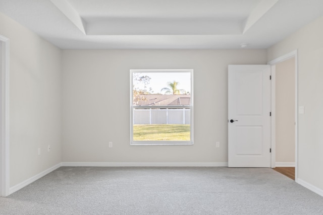 unfurnished room with a tray ceiling, carpet, and baseboards