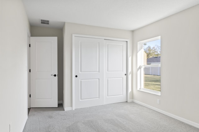 unfurnished bedroom with carpet flooring, baseboards, visible vents, and a closet