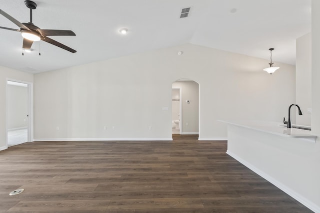 unfurnished living room featuring a sink, dark wood-style floors, arched walkways, ceiling fan, and vaulted ceiling