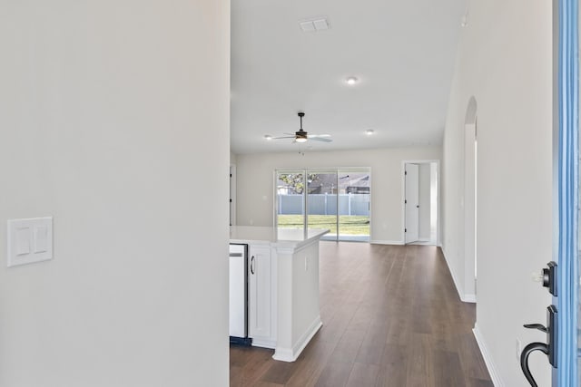 corridor featuring dark wood-type flooring, baseboards, and arched walkways