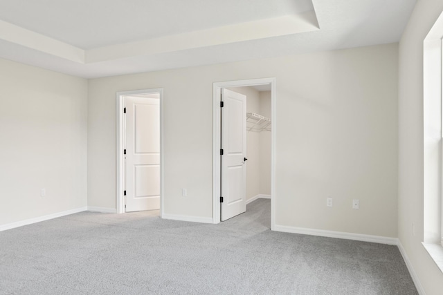 carpeted spare room featuring baseboards and a tray ceiling