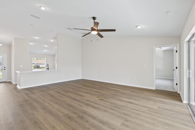 unfurnished living room with baseboards, wood finished floors, a ceiling fan, and vaulted ceiling