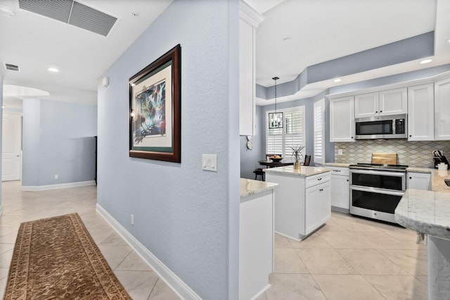 kitchen with visible vents, a kitchen island, appliances with stainless steel finishes, white cabinetry, and backsplash