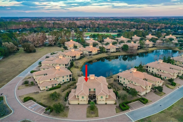 aerial view at dusk with a water view and a residential view