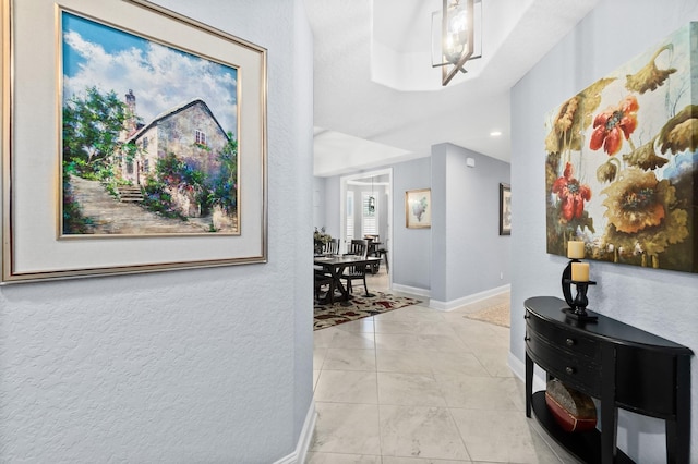 hall featuring light tile patterned flooring and baseboards