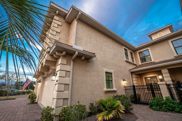 view of side of home featuring a garage, fence, and stucco siding