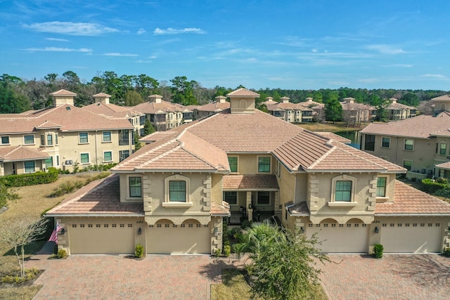 mediterranean / spanish home with a garage, a residential view, driveway, and stucco siding