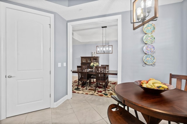 dining area with light tile patterned flooring, an inviting chandelier, and baseboards