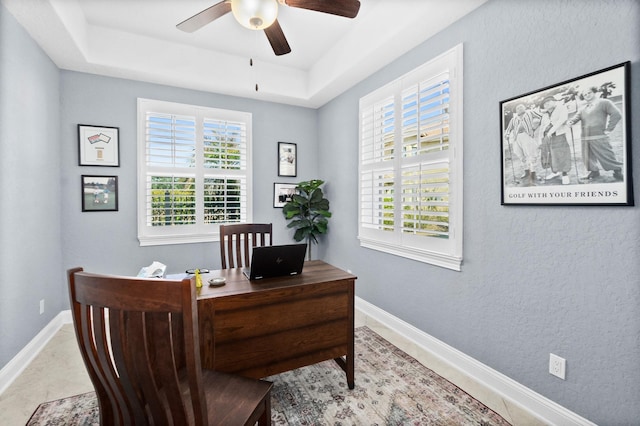 home office featuring a raised ceiling, a healthy amount of sunlight, and baseboards