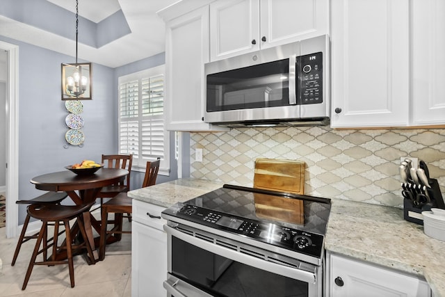 kitchen featuring light stone countertops, appliances with stainless steel finishes, white cabinets, and pendant lighting