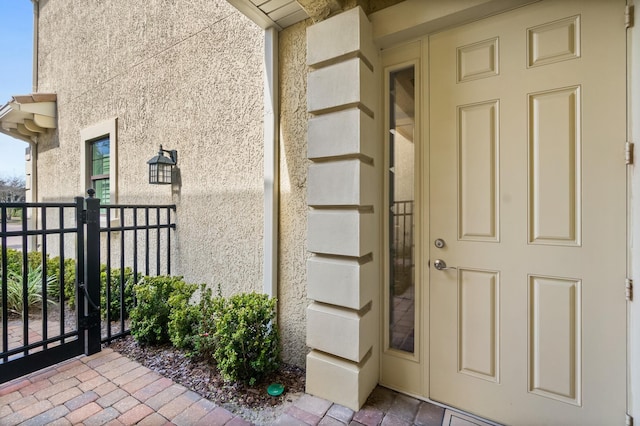 doorway to property featuring a gate and stucco siding