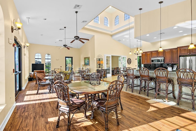 dining area with a high ceiling, visible vents, baseboards, and wood finished floors