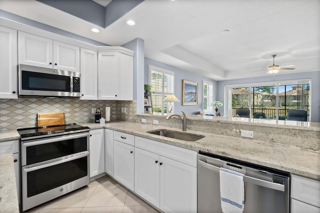 kitchen featuring stainless steel appliances, white cabinetry, a sink, and light stone countertops