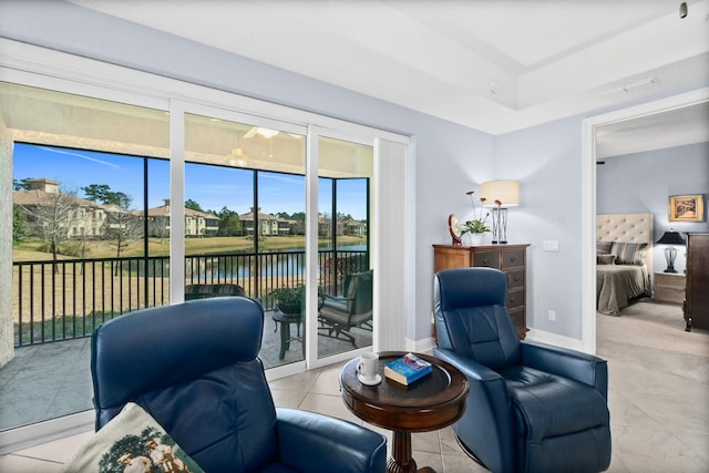 living area featuring light tile patterned floors, a water view, and baseboards