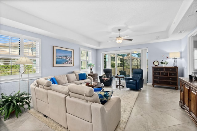 living area featuring a ceiling fan, a raised ceiling, visible vents, and light tile patterned floors