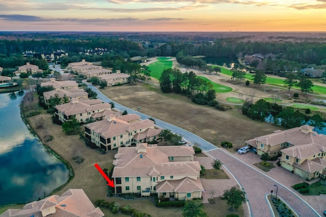 aerial view at dusk with a water view and a residential view