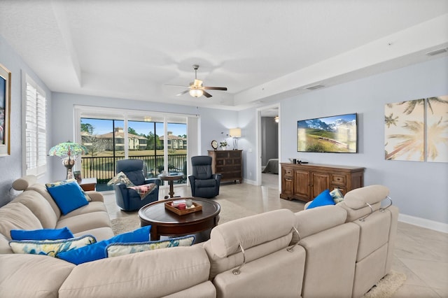 living room featuring a ceiling fan, a tray ceiling, visible vents, and baseboards