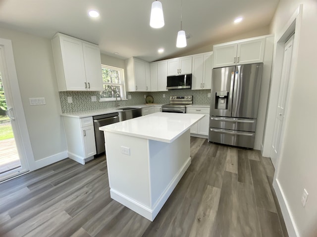 kitchen featuring dark wood-type flooring, white cabinets, hanging light fixtures, appliances with stainless steel finishes, and a kitchen island