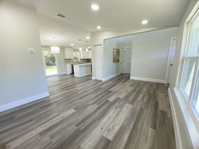 unfurnished living room with an inviting chandelier, dark hardwood / wood-style floors, and vaulted ceiling