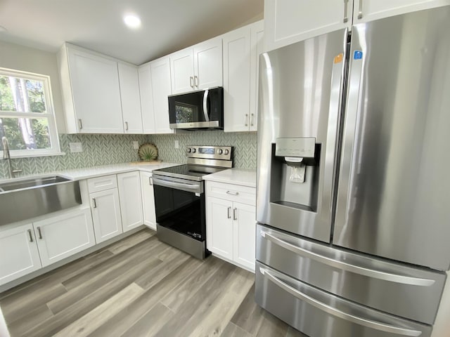 kitchen with light hardwood / wood-style flooring, white cabinets, and stainless steel appliances