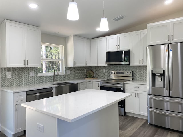 kitchen featuring white cabinets, decorative light fixtures, a center island, and appliances with stainless steel finishes