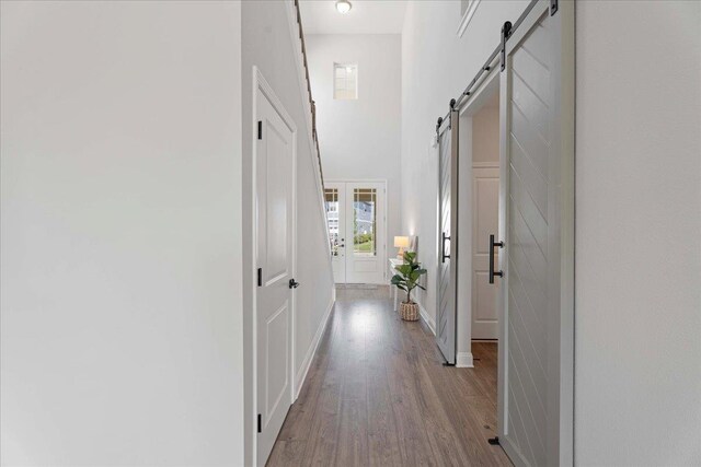 295 Ferndale Way, Saint Augustine, FL 32092 - hall with a barn door, wood finished floors, a towering ceiling, and baseboards