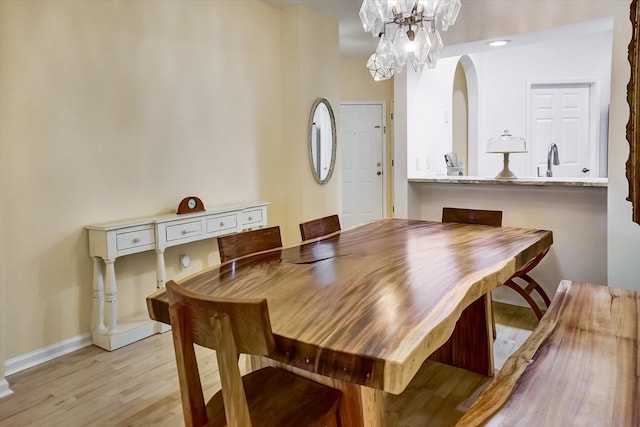 dining area featuring a notable chandelier, light wood-type flooring, and sink