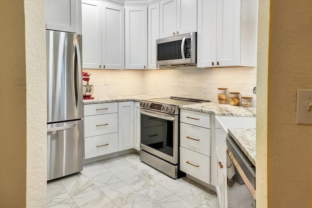 kitchen featuring white cabinets, appliances with stainless steel finishes, tasteful backsplash, and light stone counters