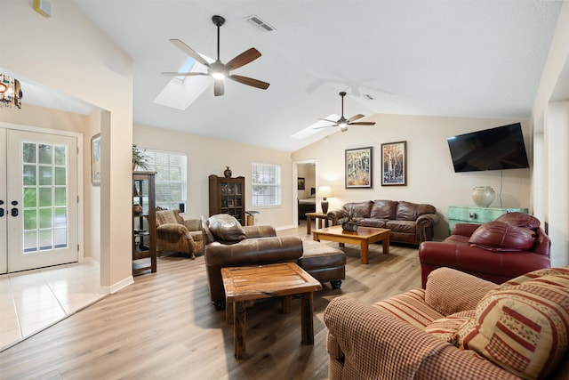 living room with lofted ceiling with skylight, light hardwood / wood-style flooring, and ceiling fan