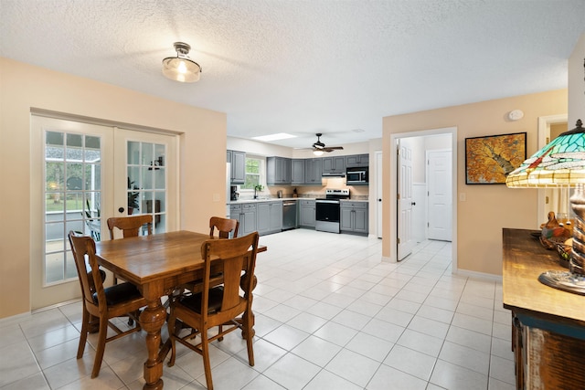 dining area featuring ceiling fan, french doors, light tile patterned floors, and a textured ceiling