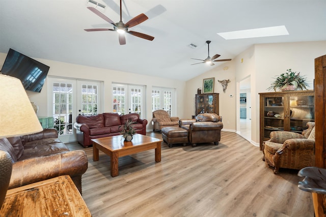 living room with ceiling fan, a skylight, light hardwood / wood-style flooring, and french doors