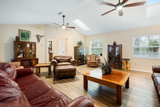 living room featuring a skylight, ceiling fan, high vaulted ceiling, and light wood-type flooring