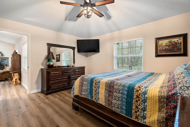 bedroom featuring ceiling fan, light hardwood / wood-style floors, and a textured ceiling