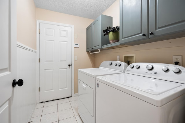 washroom with cabinets, separate washer and dryer, a textured ceiling, and light tile patterned floors