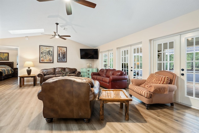 living room with light hardwood / wood-style floors, lofted ceiling with skylight, a wealth of natural light, and french doors