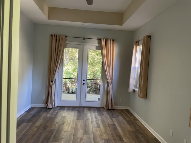 doorway with a tray ceiling, dark wood-type flooring, ceiling fan, and french doors